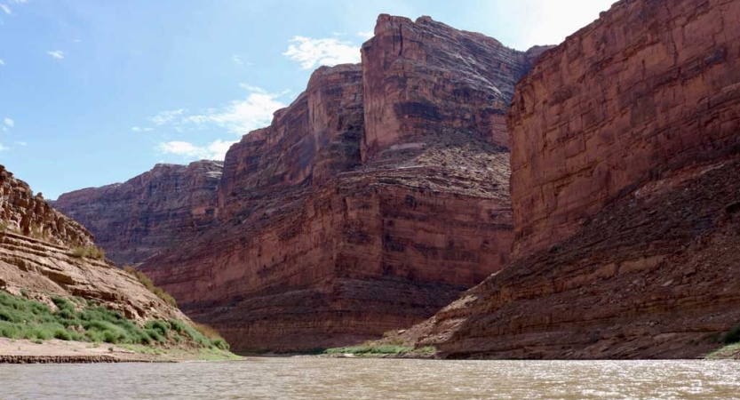 a river flows between tall, red canyon walls